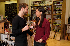 Ein Mann und eine Frau genießen in der Vinothek Stadlober ein Glas Wein