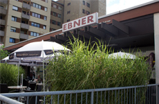 Das Café Ebner, ein Schirm der Terrasse in der frischen Luft und mit Sträuchern umgeben