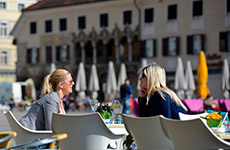 Two ladies are sitting on the main square and drinking coffee