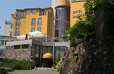 Das Hotel Landskron mit seinem Restaurant "Am Schiffertor", ein gelbliches, großes Gebäude mit dem Haupteingang und Mauer bzw. Wand aus Stein