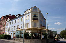 Die Café - Konditorei Mandl, ein Eckhaus neben der Mur, hellblau und dahinter blauer Himmel