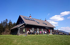 Das Almgasthaus Schweizeben, eine Hütte aus Holz, dahinter der Wald