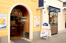 Die Bäckerei Albin Sorger, der Rundbogen als Eingang, gelbes Gebäude mit Logo der Bäckerei