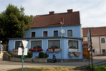 Das Gasthaus Kuhness, blaues, modernes Gebäude, mit Blumen verziehrt