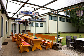 Der große, geschlossene Gastgarten des Restaurants mit Grill und großer Wiese nebenan