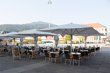 Das Kaffee Kornmesser mit vielen Plätzen zum Sitzen, weiße Sonnenschirme schützen vor der Sonne