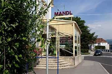 Die Café - Konditorei Mandl, ein Eckhaus neben der Mur, hellblau und dahinter blauer Himmel