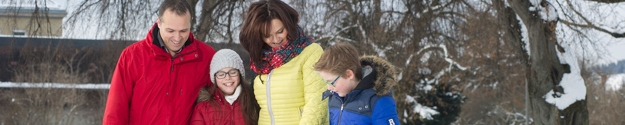 Vierköpfige Familie geht im winterlichen Stadtpark spazieren