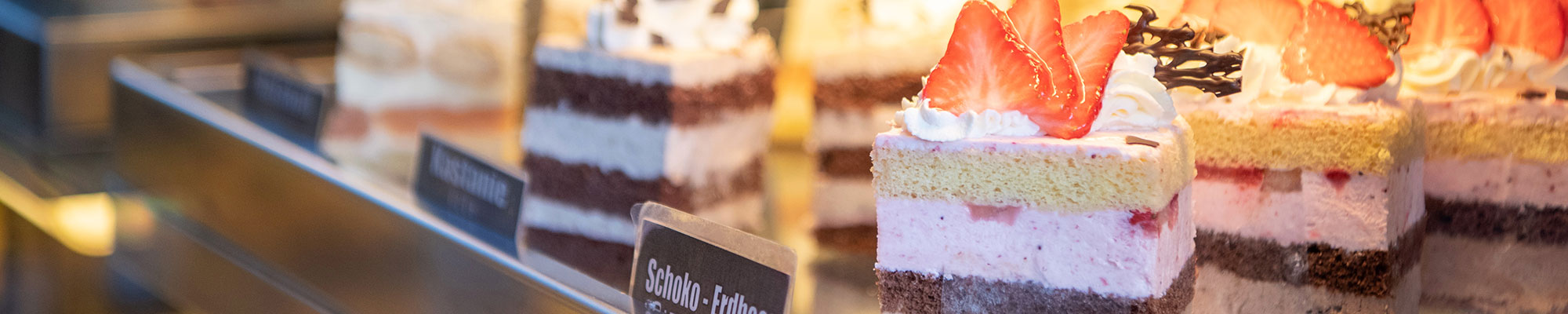 Blick in die Mehlspeis-Vitrine mit herrlichen süßen Kuchenstücken - wie Schoko-Erdbeer-Schnitte, Kasanienschnitte oder Malakoff-Schnitte